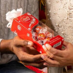 Hands holding a Lindt Lindor Candy Truffles Gift Box