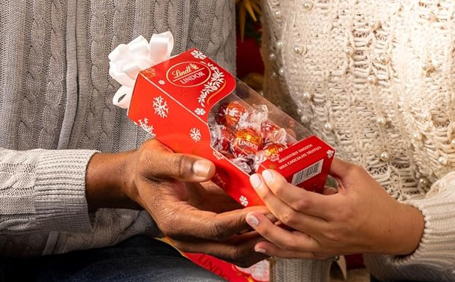 Hands holding a Lindt Lindor Candy Truffles Gift Box