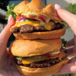 a Person Holding Two Smashburgers