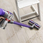 a Person Using the Dyson V8 Origin Plus Cordless Vacuum with Crevice Tool