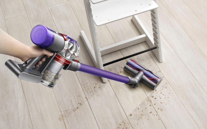 a Person Using the Dyson V8 Origin Plus Cordless Vacuum with Crevice Tool