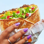 A Hand holding a Taco Bell Crunchwrap Supreme