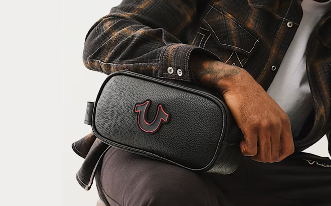 A Man Holding True Religion Horseshoe Cosmetic Bag