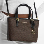 A Person Wearing Michael Kors Jet Set Travel Extra Small Logo Top Zip Tote Bag