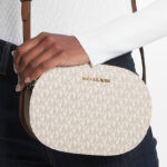 A Person Wearing Michael Kors Jet Set Travel Medium Signature Logo Crossbody Bag in Vanilla Color