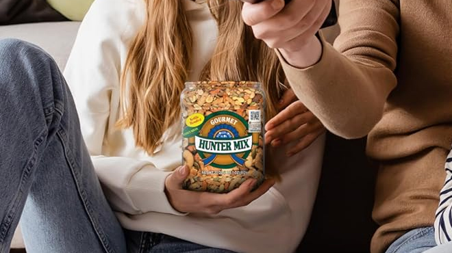 A person holding a Southern Style Nuts Gourmet Hunter Mix container