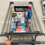 A person pushing a shopping cart at Walgreens filled with Personal Care items