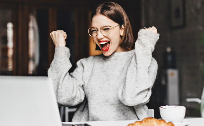 Ecstatic Young Woman Looking at Her Laptop and Making Yes Gesture