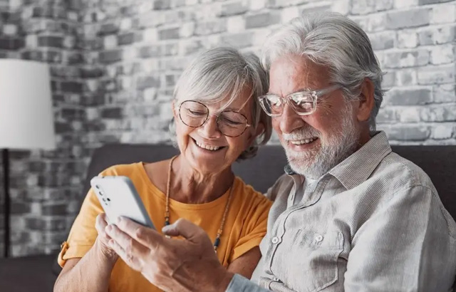 A Senior Couple Looking at a Phone and Smiling