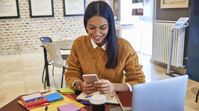 A Smiling Lady Looking at her Phone Surrounded by Notebooks