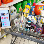 A Hand Holding a Phone in Front of a Walgreens Shopping Cart