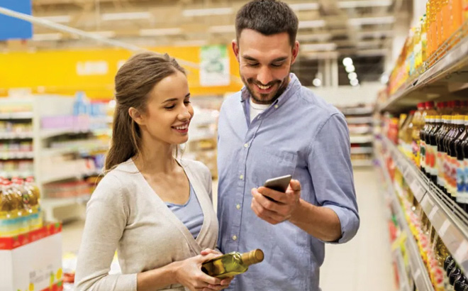 Two People Looking at Aisle Cashback Offer on Their Phone and Smiling in a Store Aisle